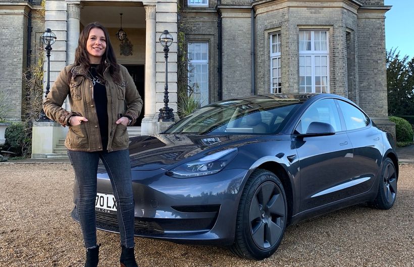 Ginny Buckley with a Tesla Model 3 in front of posh house